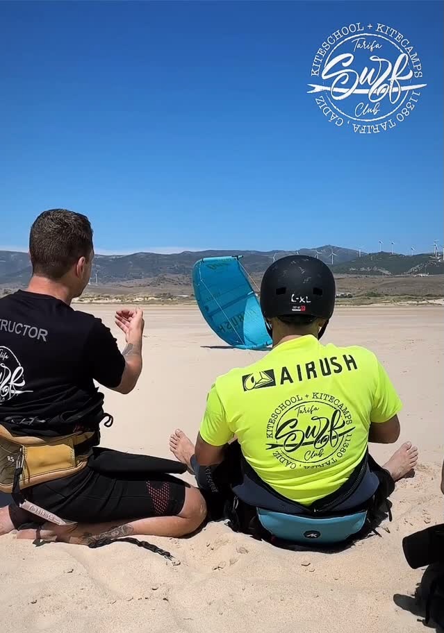 Kitesurfers training at Tarifa Surf Club with instructors on the beach, using Airush, Blankforce, and AK kiteboarding gear during a German-oriented Progress Kite Camp.